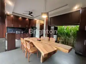Elegant dining room in a modern villa featuring a large wooden table and contemporary kitchen design.