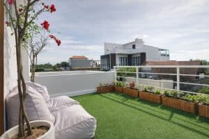 Balcony of a modern tropical villa with lush green artificial grass and stylish outdoor seating.