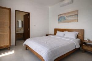 Elegant bedroom with minimalist tropical decor in a modern villa, featuring wooden furniture and bri.