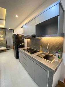 Modern kitchen with sleek gray cabinets, marble countertops, and essential appliances.