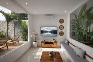 Bright modern tropical villa living room with large windows and lush greenery view.