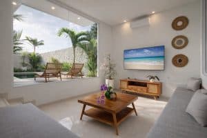 Bright tropical villa living room with large windows and outdoor garden view.