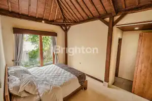 Cozy bedroom in a traditional Joglo villa featuring wooden accents and a private pool view. Perfect.