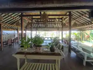Bright open-air restaurant with wooden beams and lush greenery, perfect for relaxing dining experien.