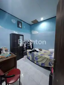 Bedroom interior with a bed, wardrobe, and cluttered desk in a compact space.